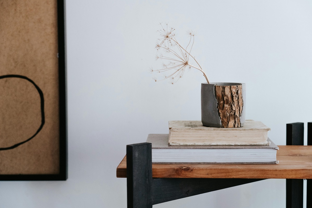 modern, handmade vase with dried cotton stems place on top of a book