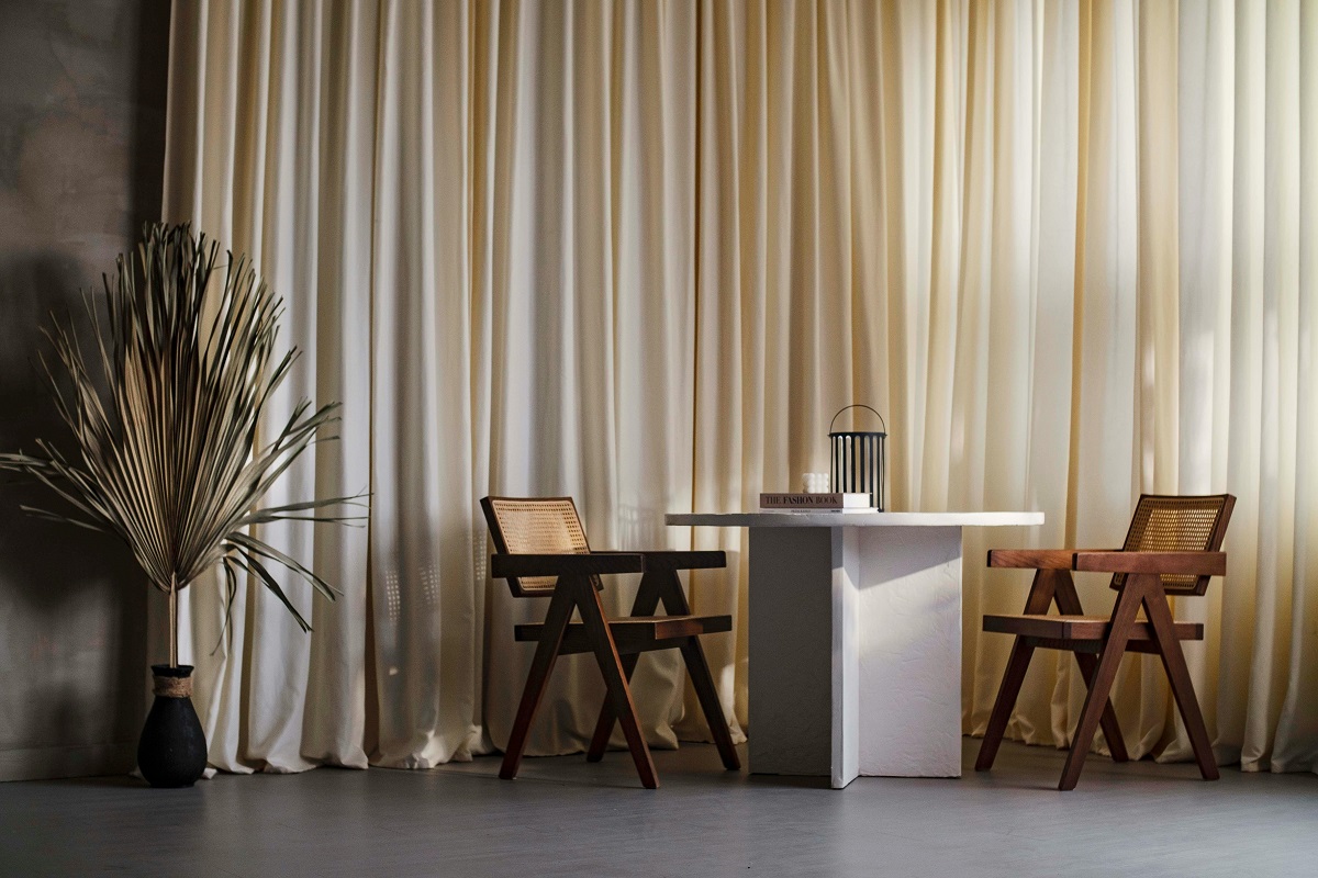 small table with two chairs near cream-colored curtains