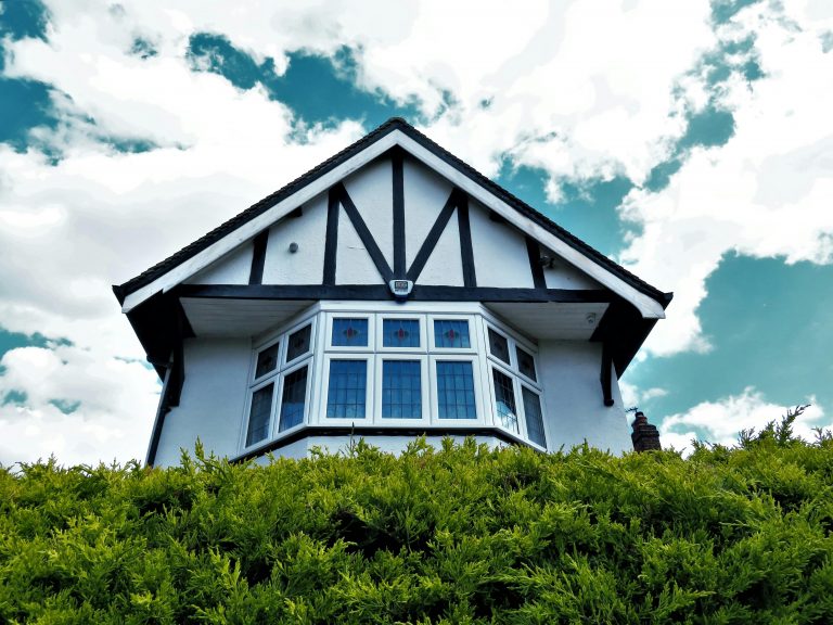 tudor style home rising above green hedges